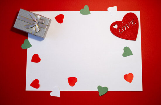 Banner. Velentines day or wedding scene mockup with blank card, paper hearts confetti and red background. Gray gift box, empty space for your texst, top view flat lay
