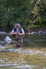 Fly fisherman using flyfishing rod in beautiful river.