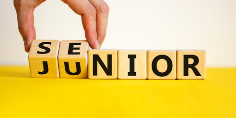 From junior to senior symbol. Businessman turns cubes and changes the word 'junior' to 'senior'....