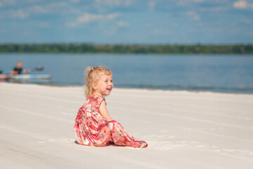 A little girl in a beautiful sarafna plays in the sand on the beach