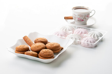 cup of hot tea marshmallow cookies cinnamon selective focus on white background high key