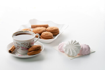 cup of hot tea marshmallow cookies cinnamon selective focus on white background high key