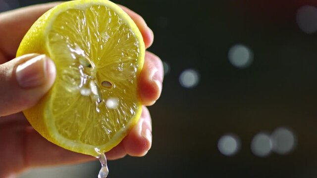 Close-up, a woman hand is squeezing a lemon in slow motion. Lemon squeezed in slow motion.