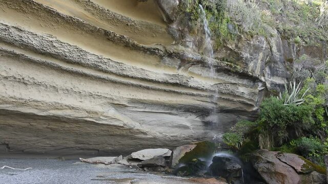 Small waterfall flowing over the stratified cliffs at the end of the Truman Track, Paparoa National Park, New Zealand.