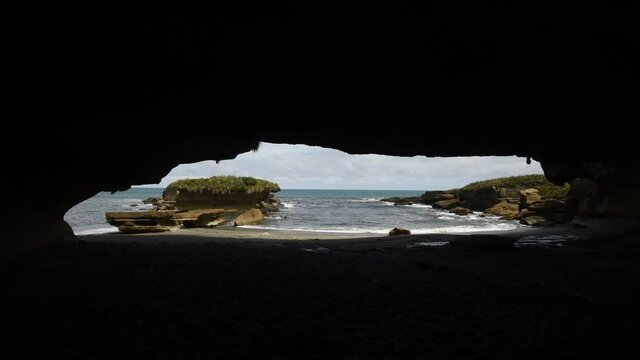The sea and beach at the end of the Truman Track, Paparoa National Park, New Zealand, viewed from within a massive cavern in the cliff.