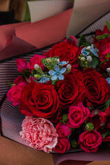 Big bouquet with red roses and mix flowers in hands, floral gift for woman