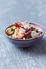 Salad with tuna and cherry tomatoes. Wooden background. Close up. Copy space.