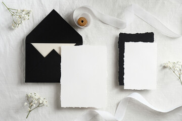 Wedding invitations mockups and black envelopes on textile background with flowers and white...