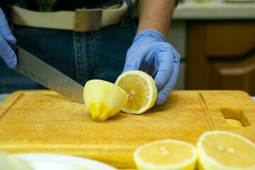 The process of making limoncello lemon liqueur at home. A man cuts lemons without zest into halves.