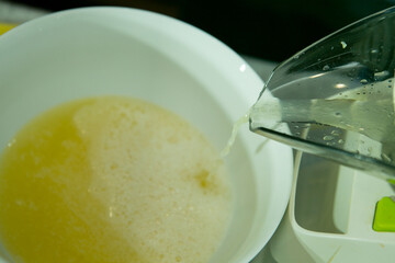 The process of making limoncello lemon liqueur at home. Fresh lemon juice flows out of the food...