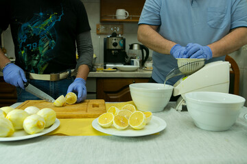 The process of making limoncello lemon liqueur at home. Two men are working in the kitchen. One of...