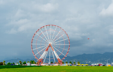 High ferris wheel in an amusement park against the backdrop of the sea and mountains. Georgia. Batumi