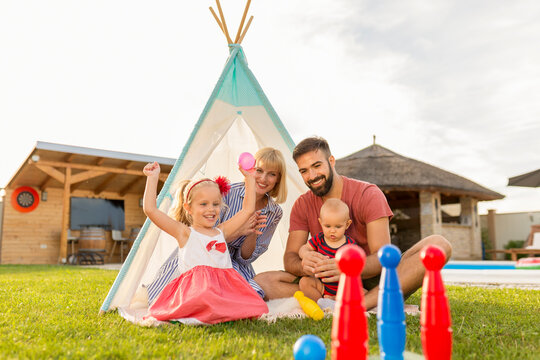 Parents playing with children while camping in the backyard