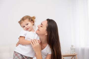 adult mother hugging her little daughter at home, having fun.