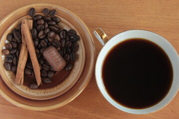 cup of coffee with beans chocolate candy and cinnamon