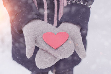 red heart lies on the fresh mittens. Winter snow. the girl dares in her palms a small red heart. Horizontal photo, close-up, top view.