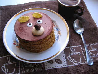 Cupcake in the form of a bear face and a cup of coffee on a towel