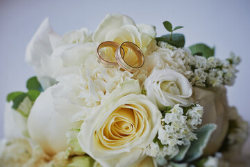 gold rings and a beautiful bridal bouquet of roses on the background. details, wedding traditions. close-up, macro