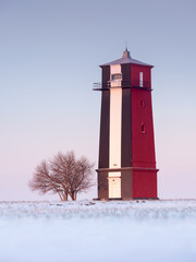 portrait view to alone lighthouse in white snow field