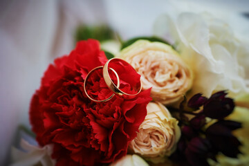 gold rings and a beautiful bridal bouquet of roses on the background. details, wedding traditions. close-up, macro