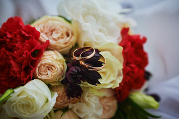 gold rings and a beautiful bridal bouquet of roses on the background. details, wedding traditions. close-up, macro