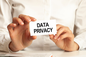 A woman in a white shirt holds a piece of paper with the text: DATA PRIVACY. Business concept.