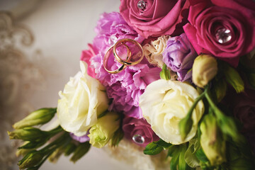 gold rings and a beautiful bridal bouquet of roses on the background. details, wedding traditions. close-up, macro
