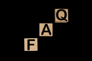 Wooden blocks with word FAQ on black baclground. Frequently asked question concept