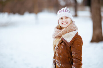 Portrait of smiling stylish girl outside in city park in winter