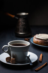 Coffee cup with a tasty cinnamon bun on background
