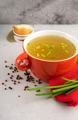 hot homemade vegeterian vegetable broth with amino acids in red bowl