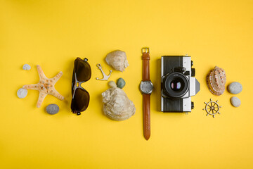 Seashells, sunglasses, watch and camera. Traveler's items in a row on yellow