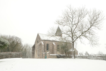 Snowstorm at the countryside with a church in the background. Winter scene with the flakes in front of the camera lens.