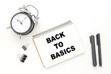 BACK TO BASICS written on a white background near pencils, a clock, a white notepad in a pot. Business concept