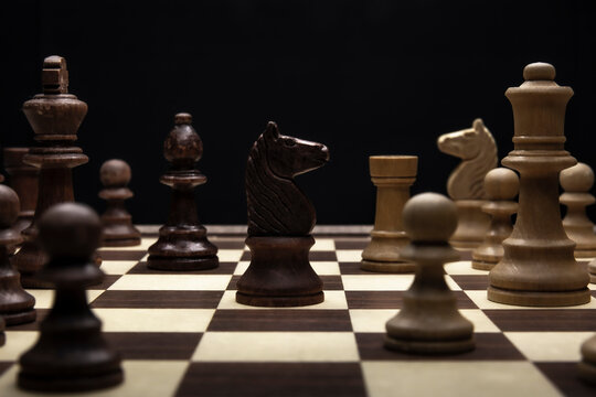Knight in a chess duel on the chessboard. Low-key concept picture of chess pieces taken in studio and concerning decision making and strategy.
