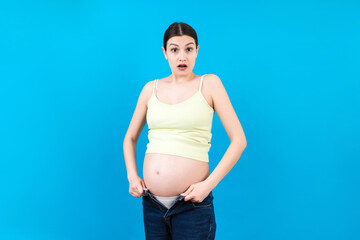 pregnant woman in unzipped jeans showing her naked belly at colorful background with copy space. Baby expecting concept