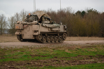 Fototapeta premium british army FV430 in motion, fully loaded with troop bergens under a tarpaulin cover 