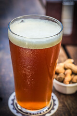 Fresh and cold tap ale beer pint with peanut on a wooden table