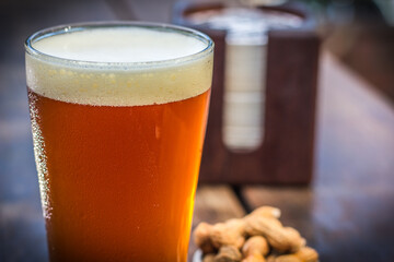 Fresh and cold tap ale beer pint with peanut on a wooden table