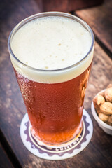 Fresh and cold tap ale beer pint with peanut on a wooden table