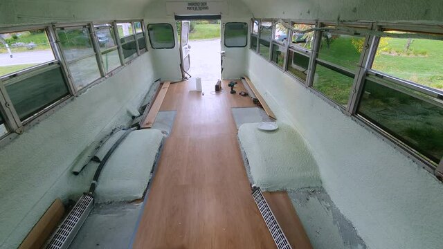 An informative video of flooring process of an American school bus, the workman is pointing hand to show the flooring specifications. 