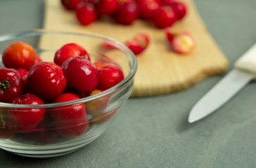 Barbados Cherry (acerola) in a bowl and a knife - Gray background