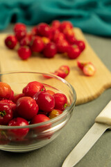 Barbados Cherry (acerola) in a bowl and a knife - Gray background