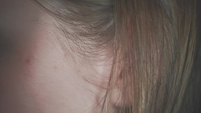 Ear of lady closeup. Lady play with her blond hair over her ear.