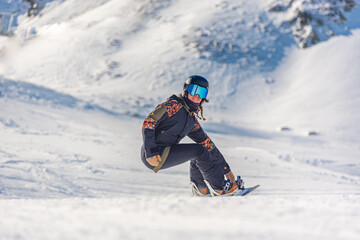 Fototapeta na wymiar Young woman snowboarder in motion on snowboard in mountains
