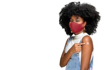 girl points to the vaccine patch on her arm, Dark-skinned teen girl points the sticker   on the arm shows she was vaccinated, wearing face protection mask, sars-cov-2 covid-19 - obrazy, fototapety, plakaty