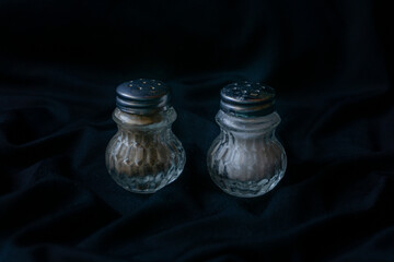 Hermosos salero y pimentero de cristal con tapa de metal plateado. Ambos se encuentran con un fondo...