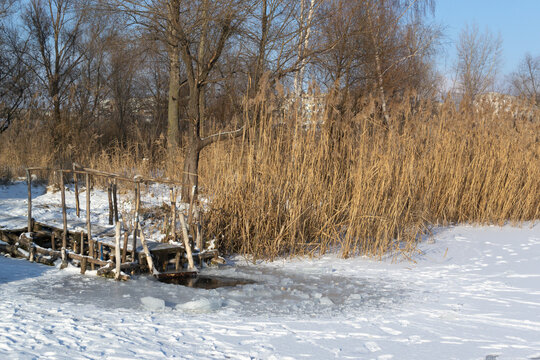 An ice-hole on a frozen river. A dip near the city. Ice bathing concept. Horizontal orientation.