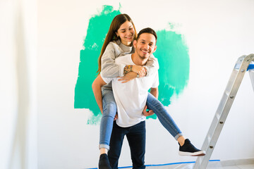 Latin man carrying his partner while doing a home renovation