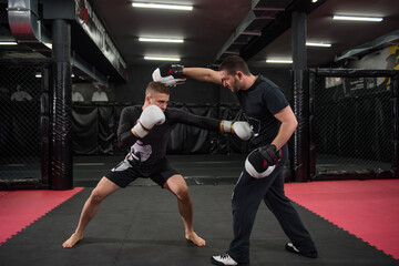 Male fighter training with his trainer - obrazy, fototapety, plakaty